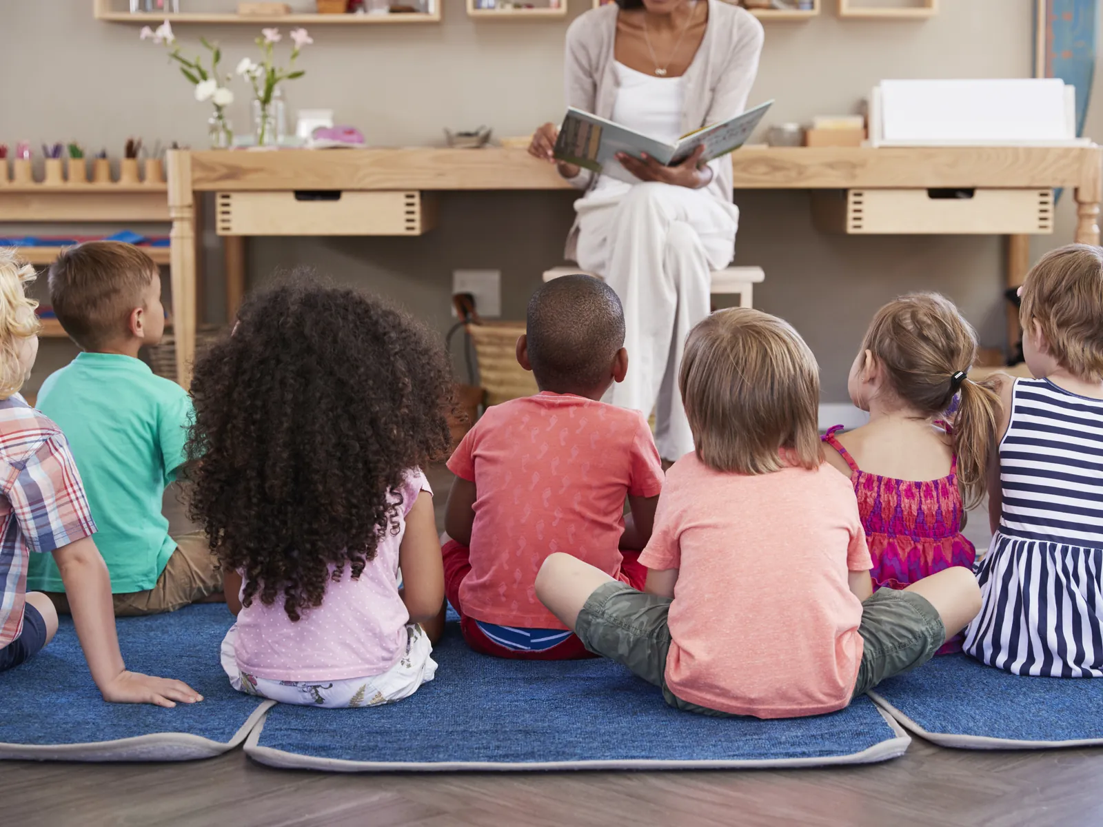 Étudiante lit une histoire à un petit groupe d'enfants en classe