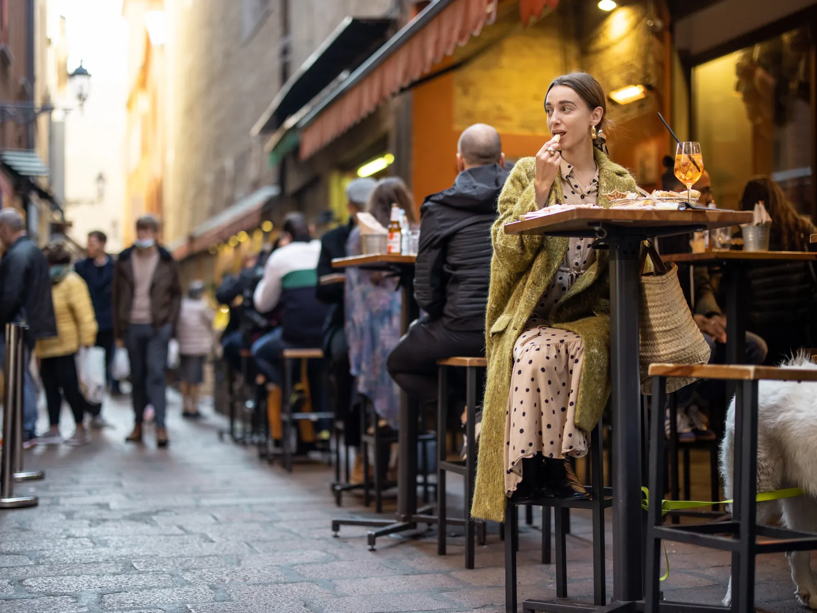 Café au coin d'une rue flamande avec du monde en terrasse
