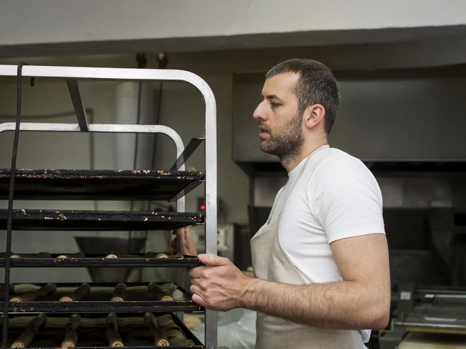 Ouvrier sortant un chariot du four dans une boulangerie industrielle