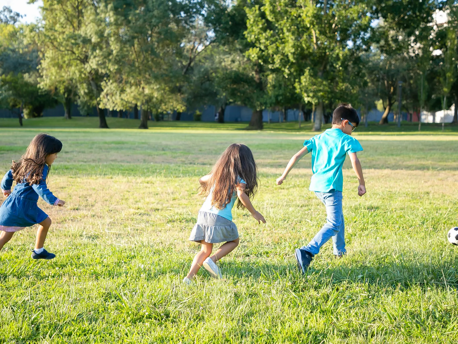 Surveillant en gilet fluo regarde des enfants jouer au football dans la cour