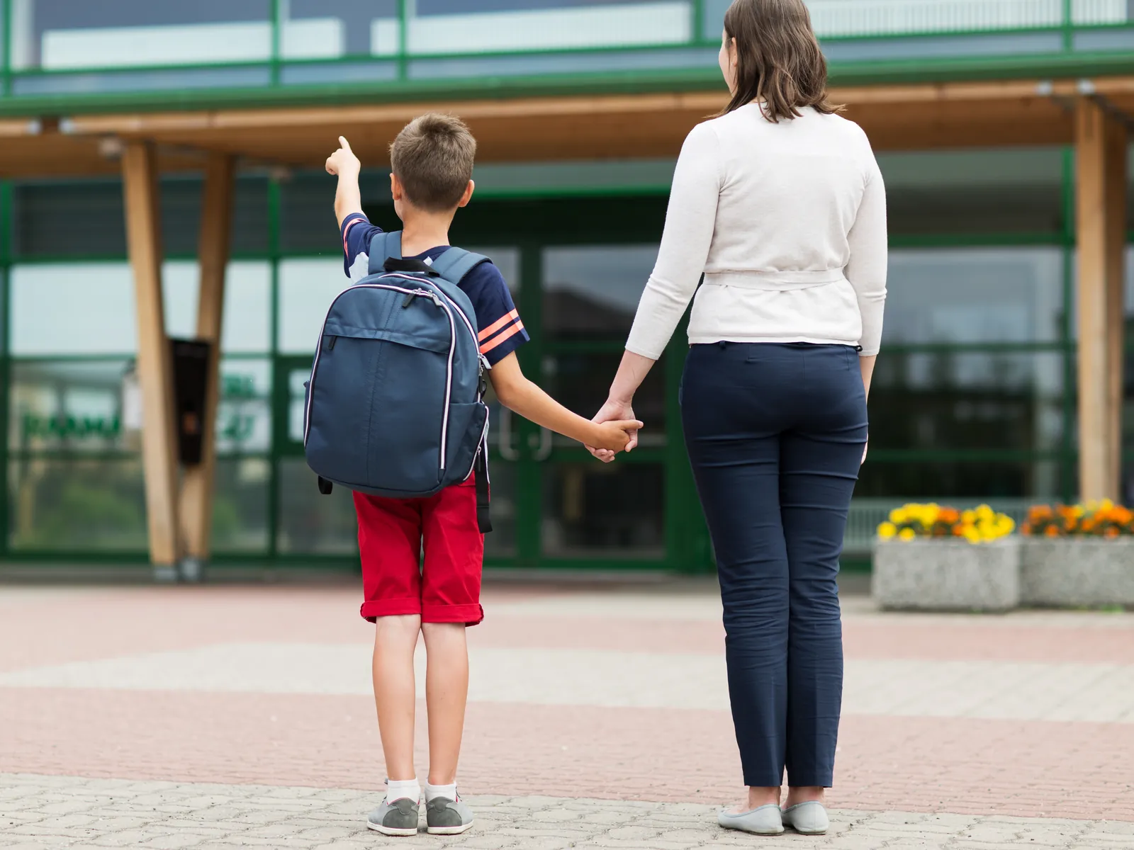 Accueillant confie un enfant et son cartable à un parent devant l'école