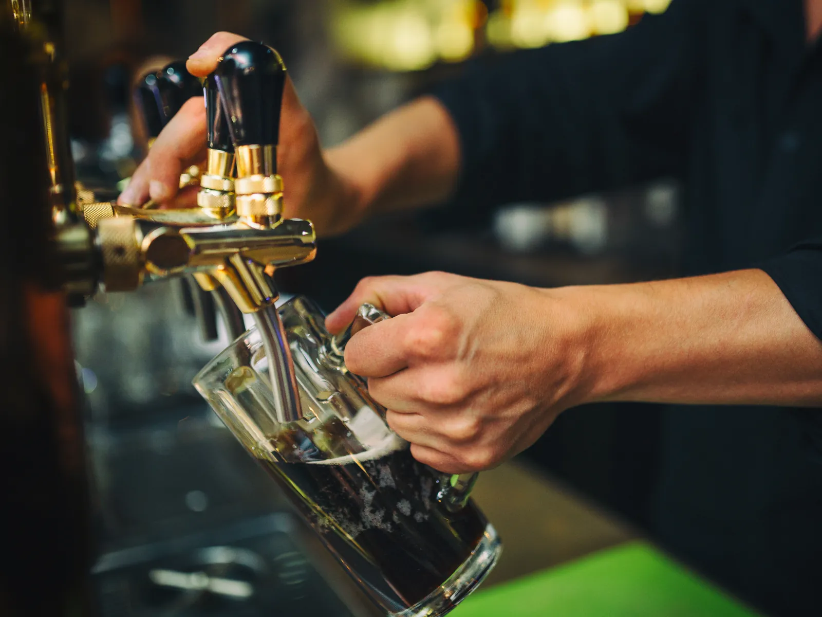 Barman qui tire une bière derrière un comptoir bondé un vendredi soir