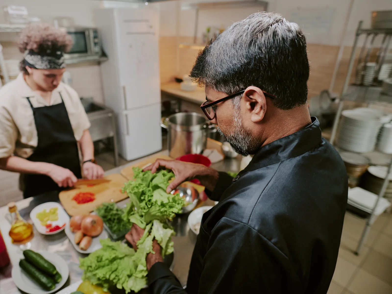 Aide de cuisine qui coupe des légumes dans une cuisine de restaurant en plein service