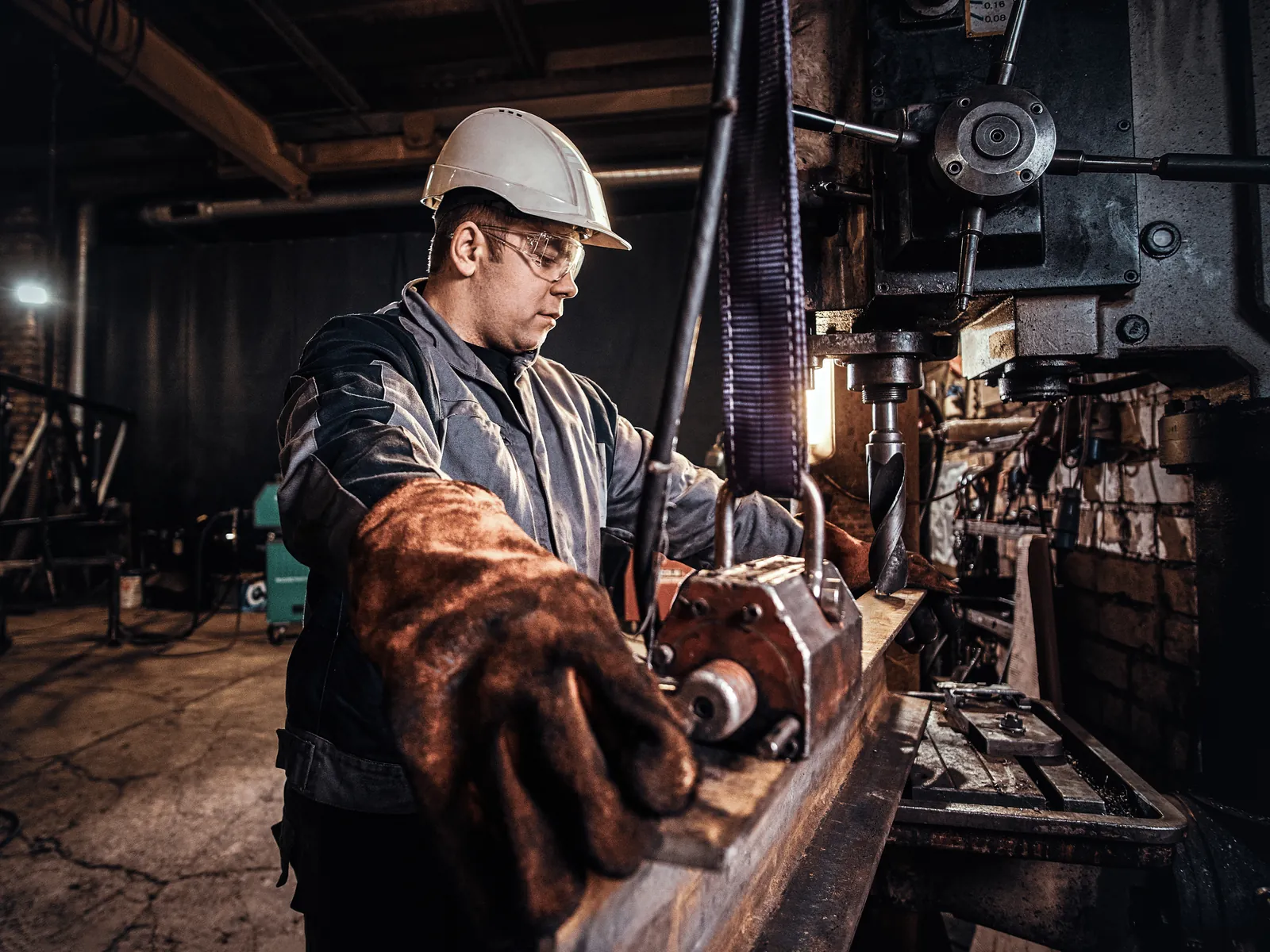 Ouvrier casqué enfilant des gants de travail dans un hall de production