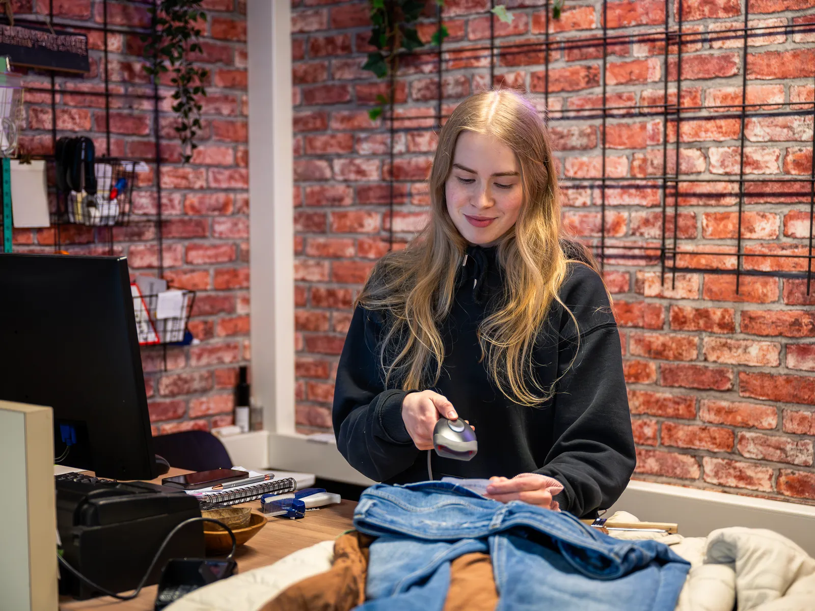 Kassamedewerker haalt een antidiefstallabel van een jas aan de toonbank