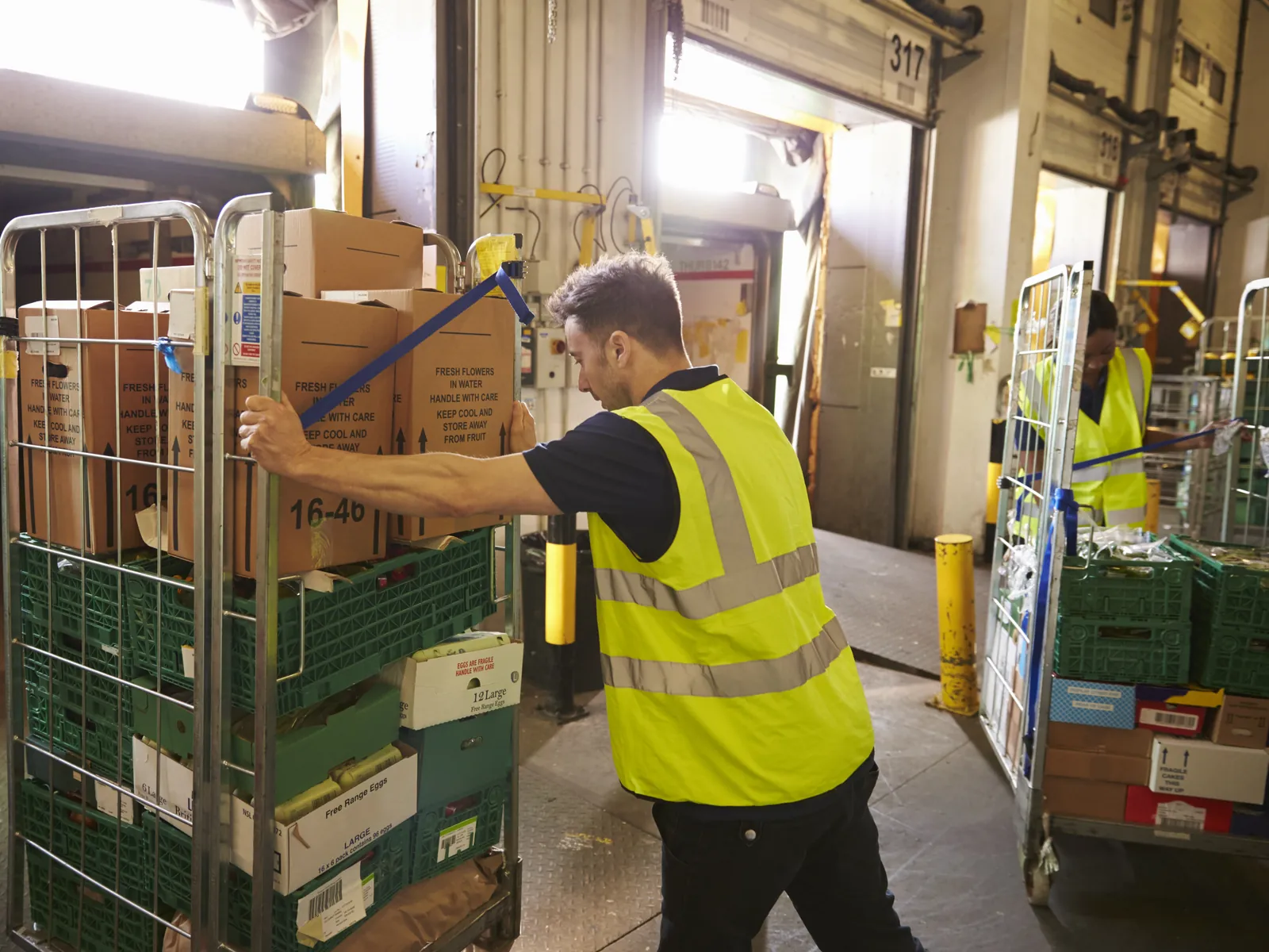 Employé pousse un roll rempli par l'entrée arrière d'un supermarché