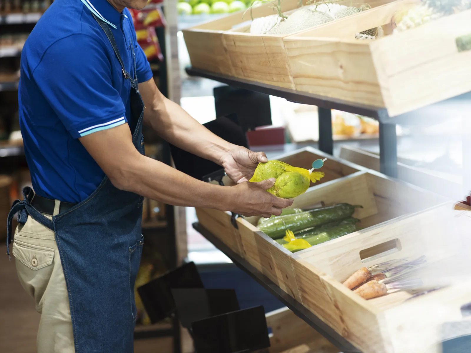 Employée trie des tomates et remplit les bacs au rayon fruits et légumes